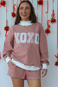 Woman wearing a pink 'XOXO' outfit with a decorative background