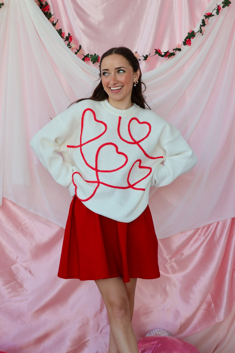 girl wearing white sweater with red heart detailing