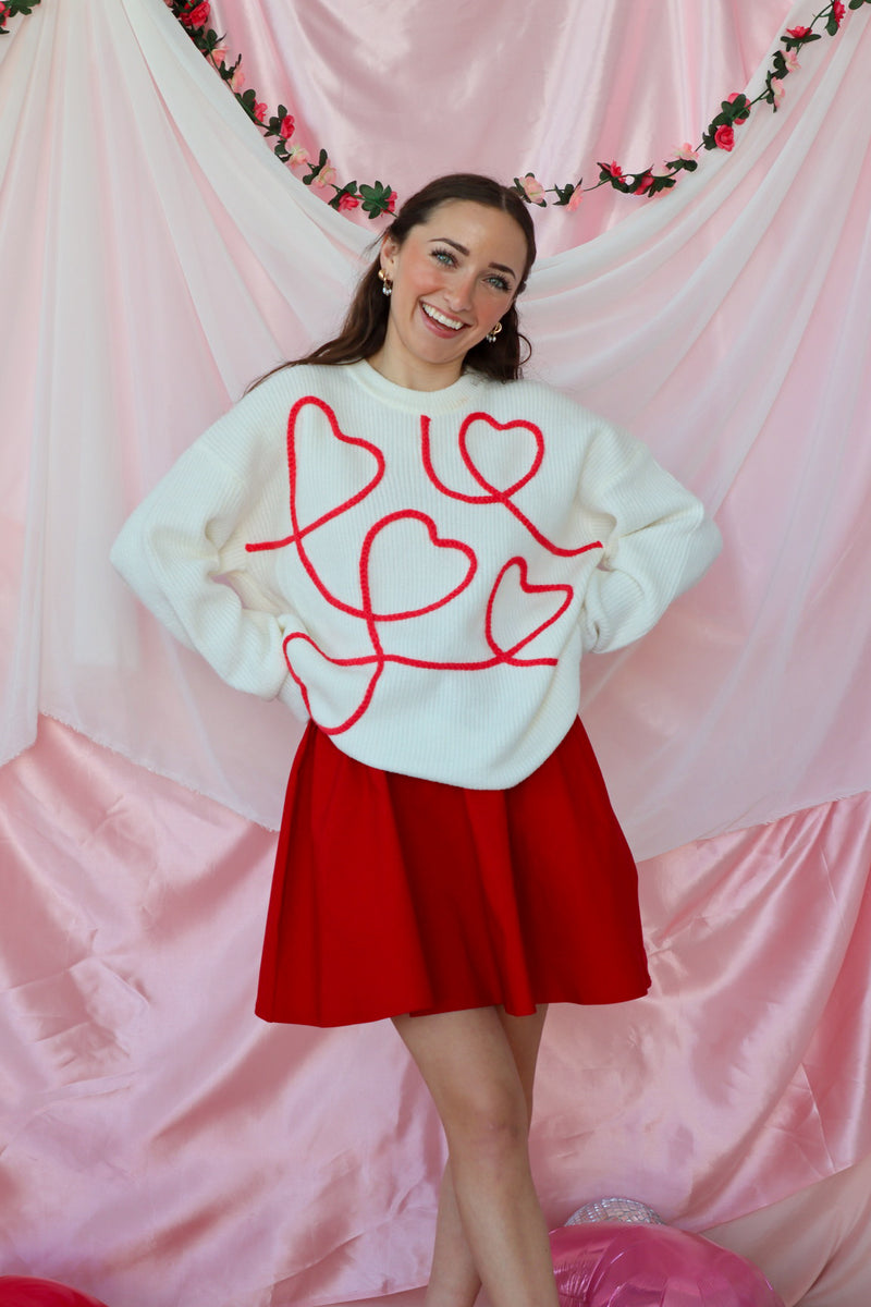 girl wearing white sweater with red heart detailing