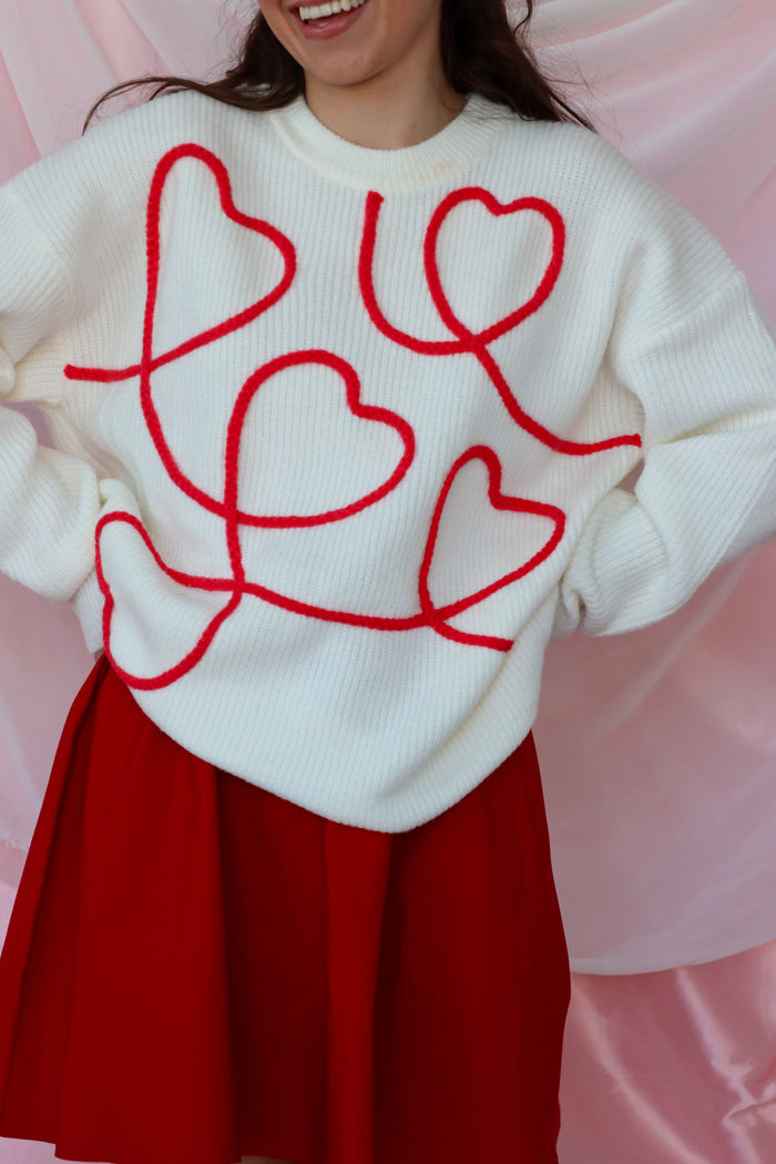 girl wearing white sweater with red heart detailing