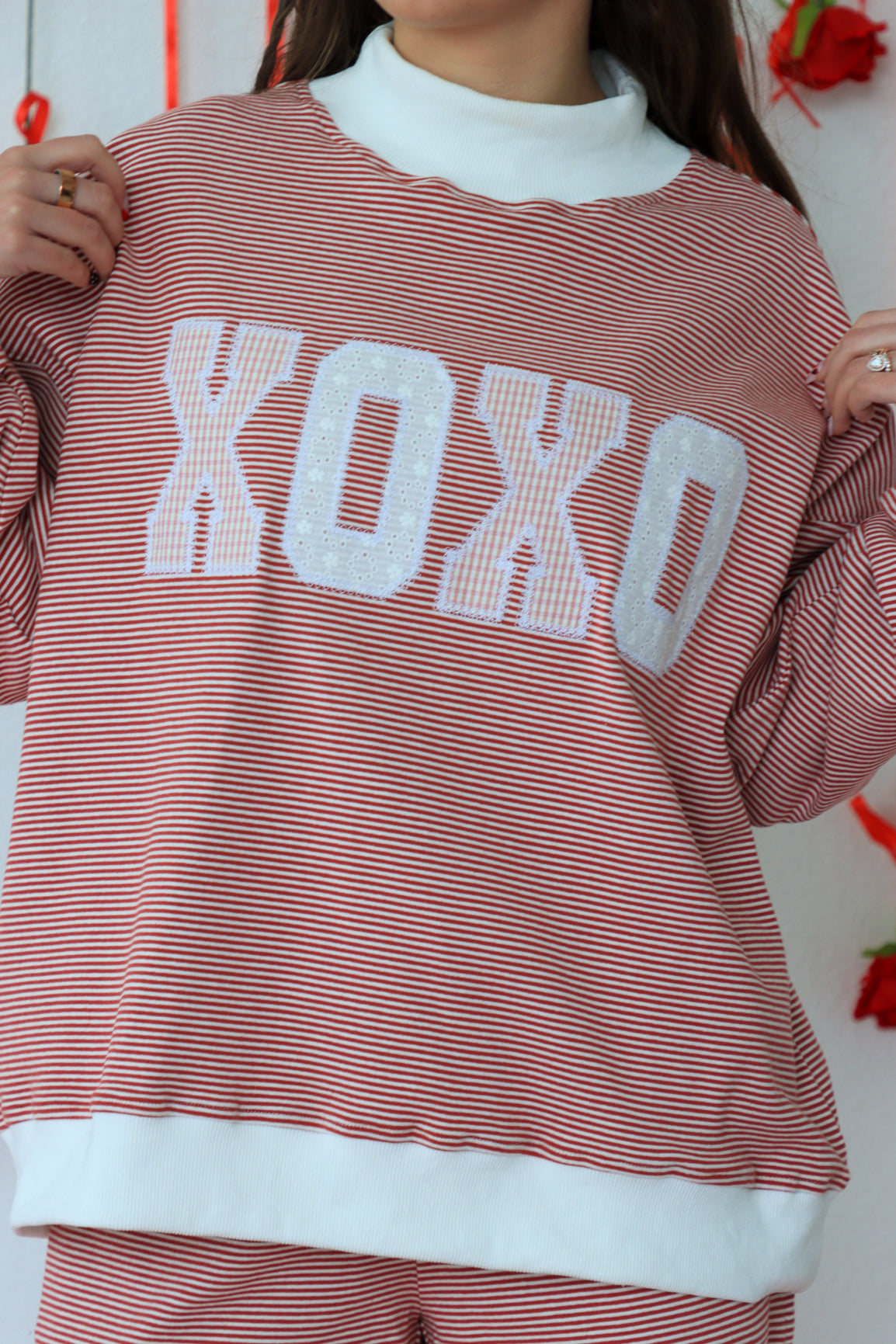 Person wearing a red and white striped sweater with 'XOXO' text.