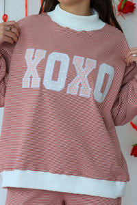 Person wearing a red and white striped sweater with 'XOXO' text.
