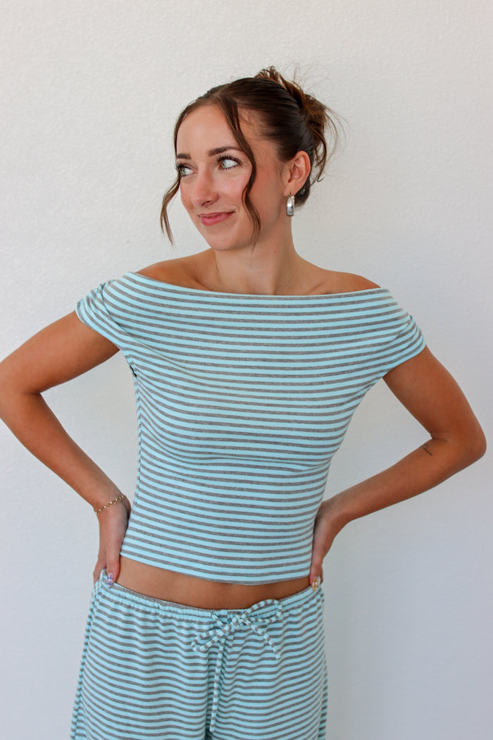 A woman modeling an off the shoulder light blue striped top and matching pants 