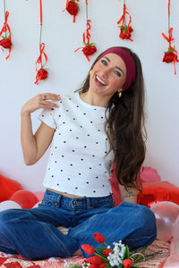 Woman sitting on a floor with red ribbons and flowers in the background