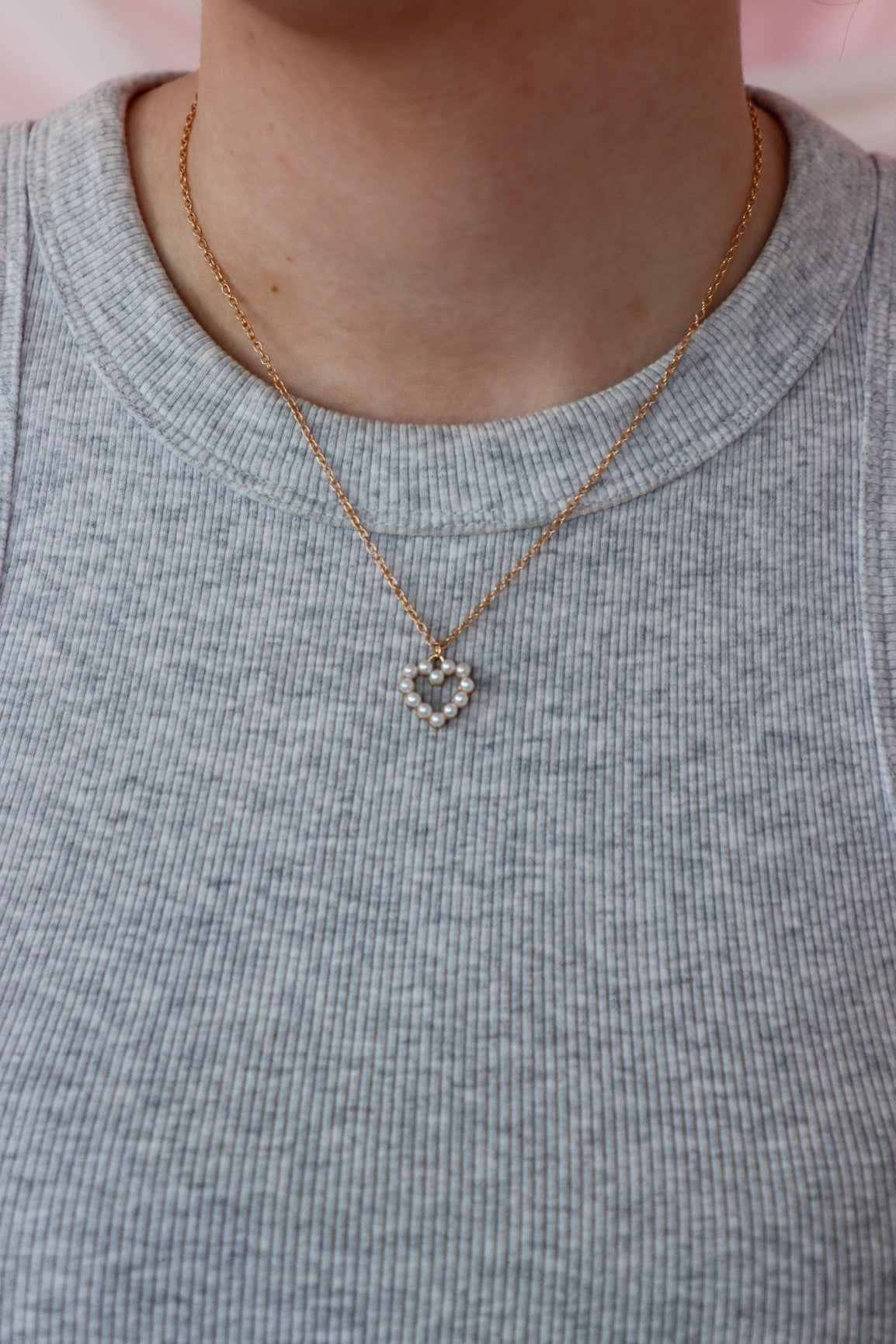 girl wearing gold and pearl heart necklace