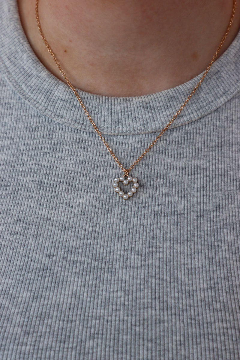 girl wearing gold and pearl heart necklace