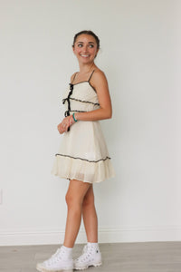 girl wearing white dress with black bow detailing