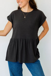 girl wearing black waffle knit peplum top