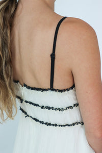 girl wearing white dress with black bow detailing