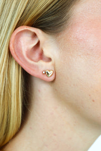 Close-up of a person wearing a gold heart-shaped earring.