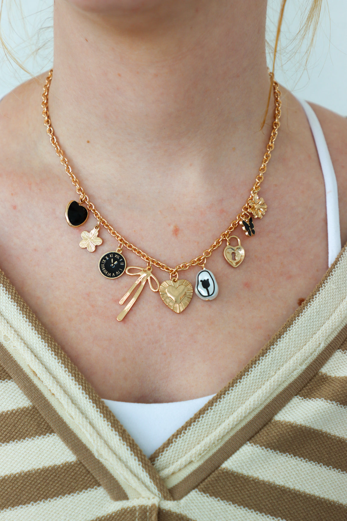 Gold necklace with various charms worn by a person