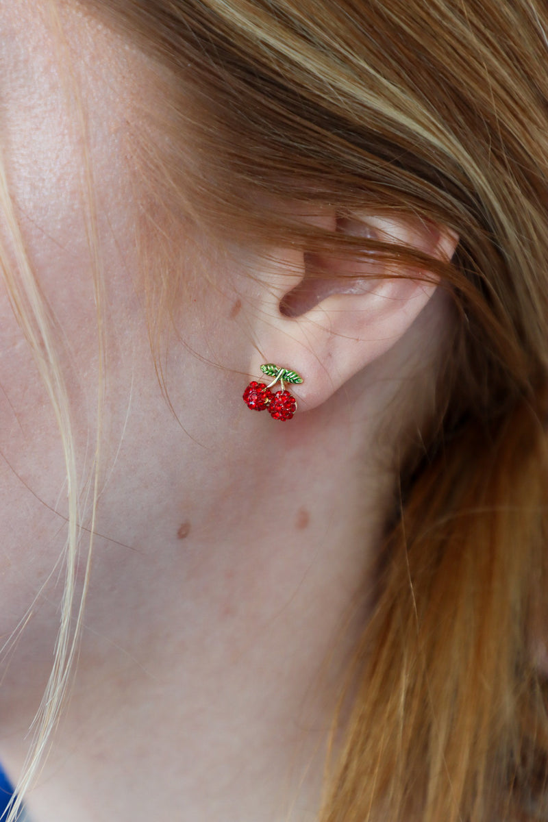 girl wearing cherry stud earrings