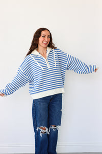Woman wearing a blue and white striped sweater and jeans against a white background