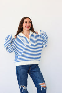 Woman wearing a blue and white striped sweater and jeans against a white background