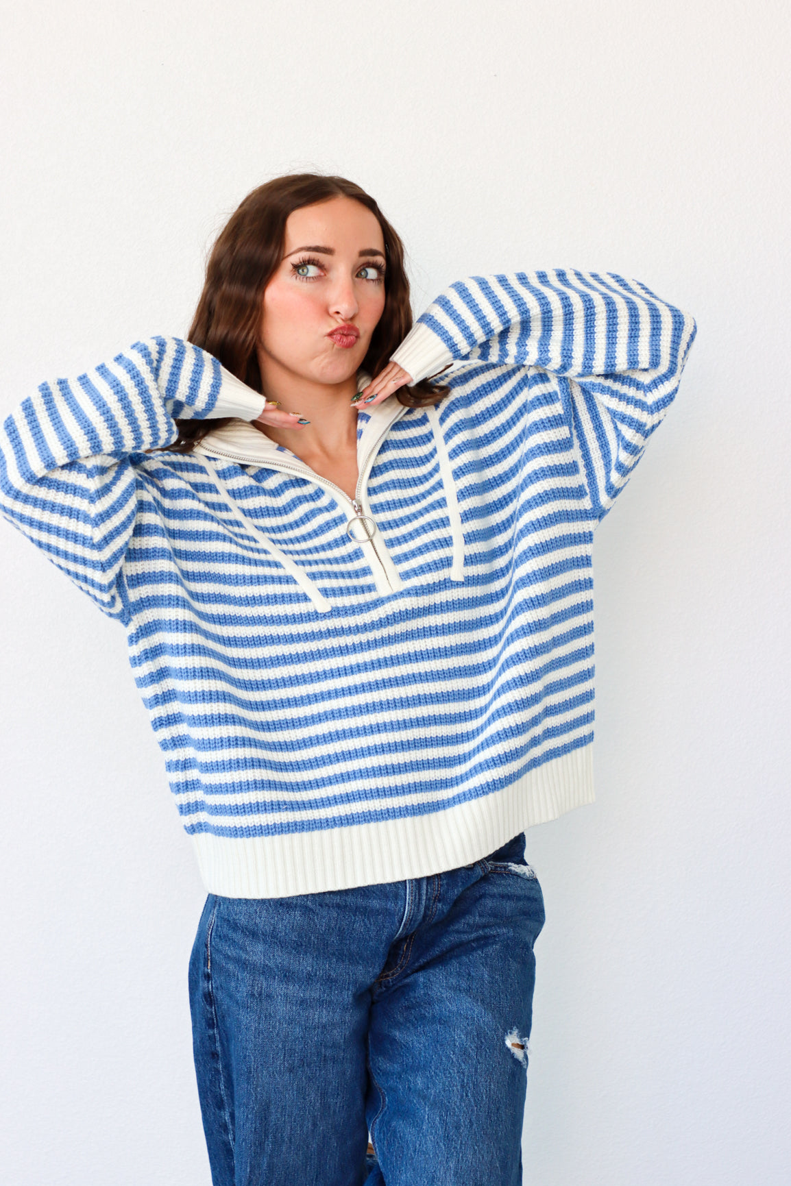 Woman wearing a blue and white striped sweater with a plain background