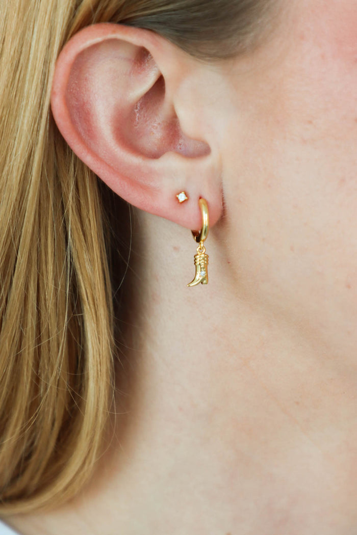 girl wearing gold cowboy boot huggie earrings