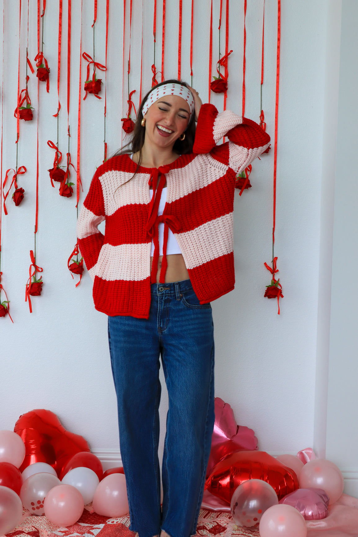 Person wearing a red and white striped sweater with a festive background of balloons and decorations.
