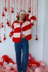 Person wearing a red and white striped sweater with a festive background of balloons and decorations.