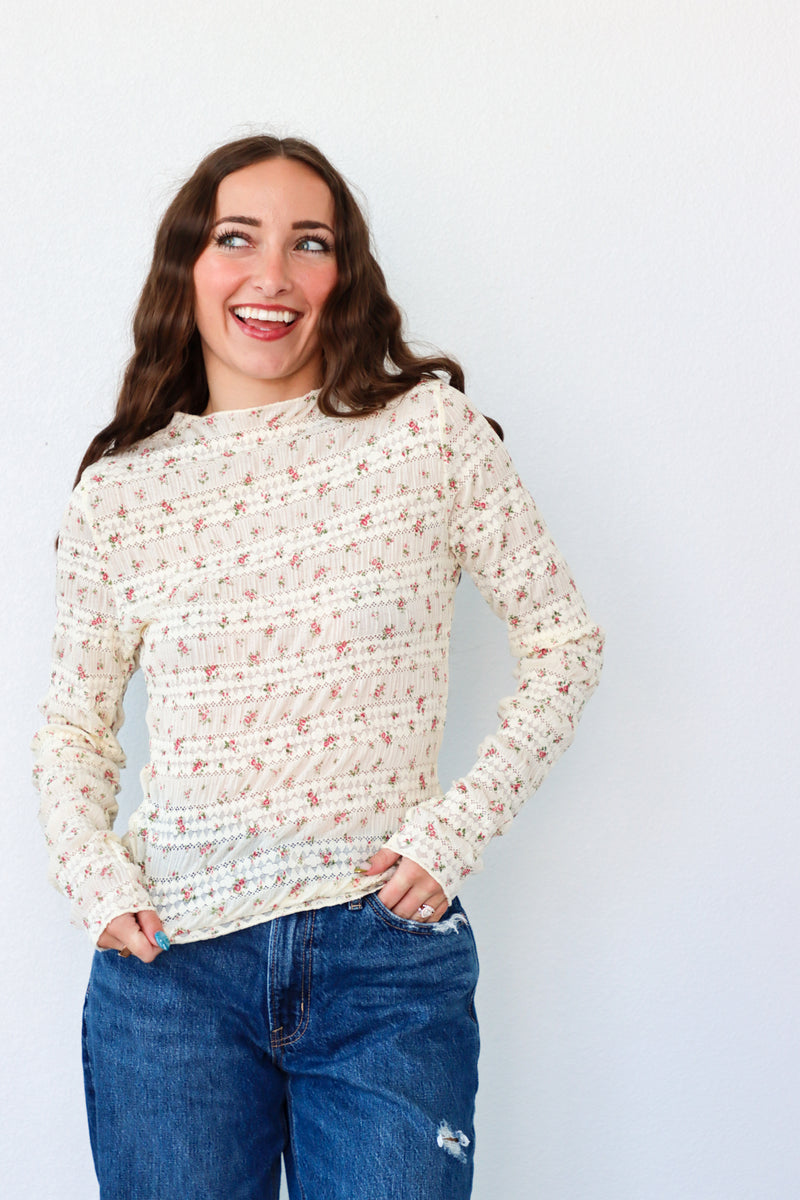 Woman wearing a patterned sweater and jeans against a plain background