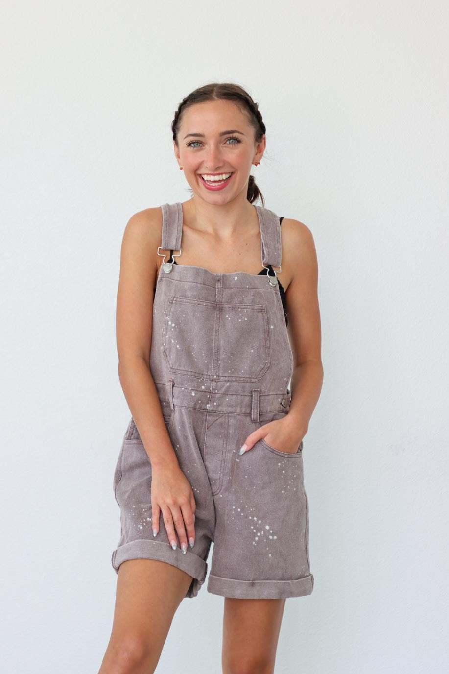 girl wearing taupe short overalls with paint splatter
