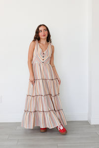 Woman wearing a striped dress with red shoes against a white wall