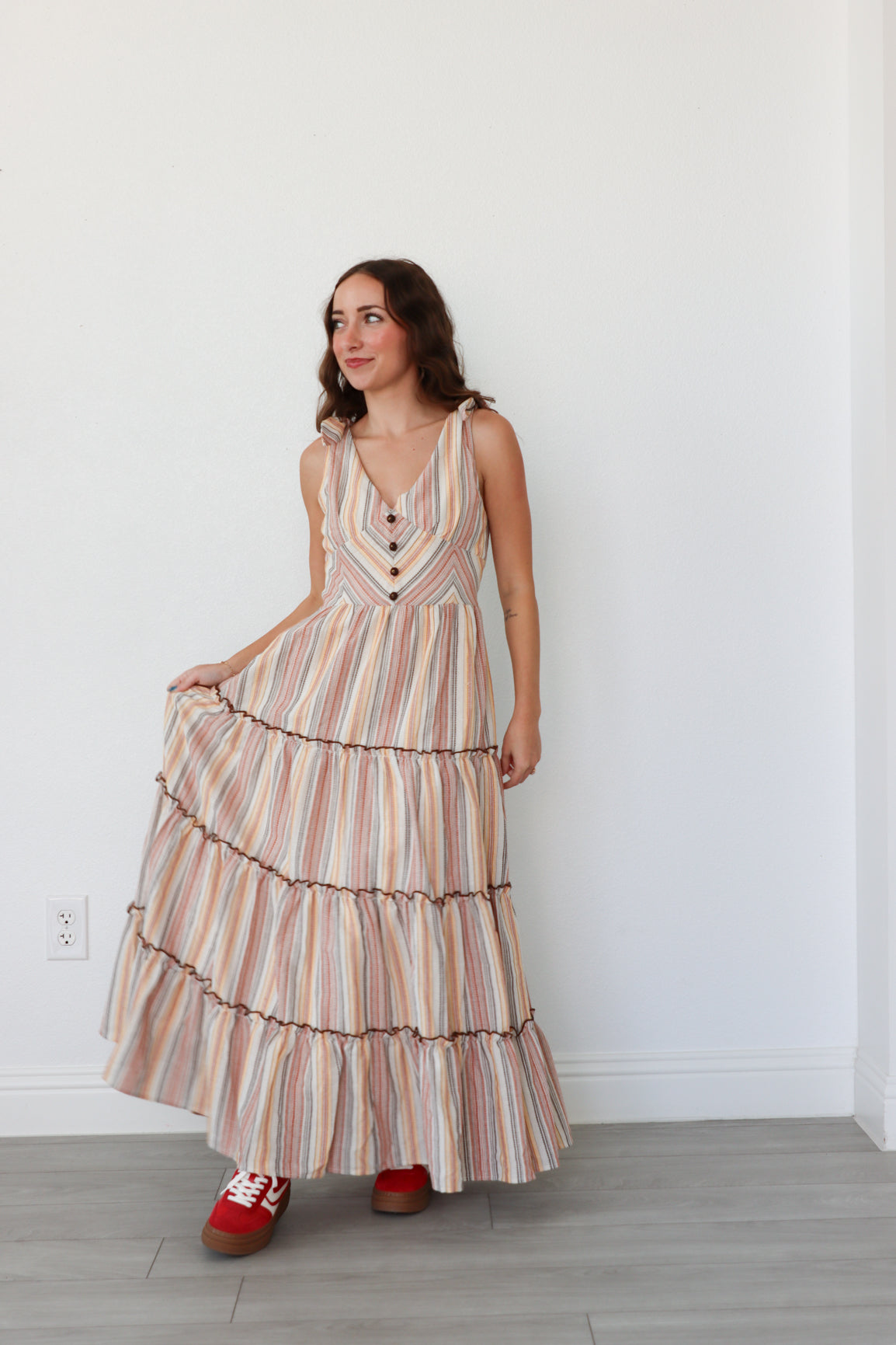 Woman wearing a striped dress standing against a white wall.