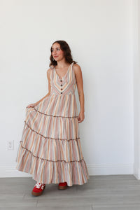 Woman wearing a striped dress standing against a white wall.