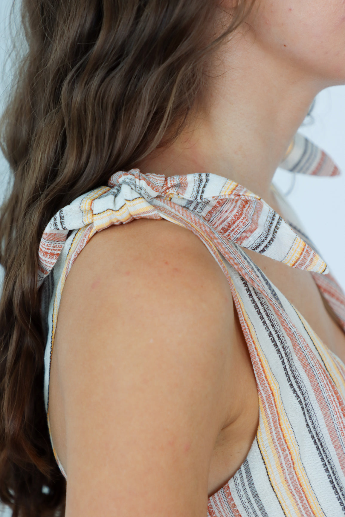 Close-up of a person wearing a striped sleeveless top with a blurred background