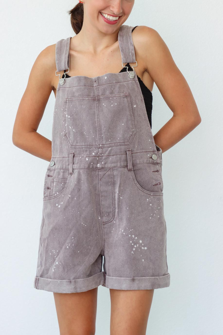 girl wearing taupe short overalls with paint splatter