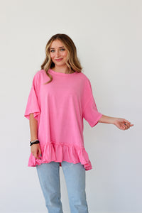 Woman wearing a pink ruffled top and light blue jeans against a white background