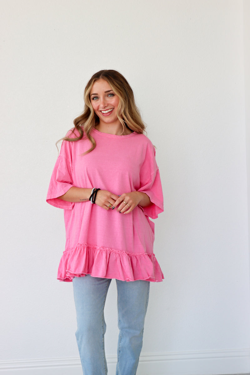 Woman wearing a pink ruffled top and light blue jeans against a white background