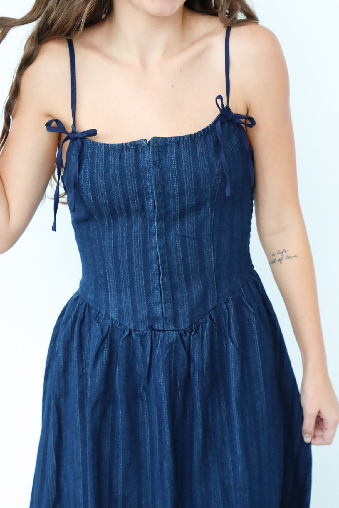 Woman wearing a blue dress with thin straps on a white background