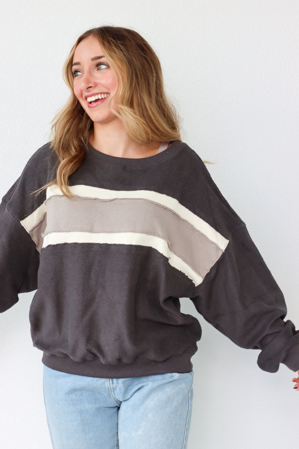Woman wearing a dark gray sweatshirt with color-block design against a white background