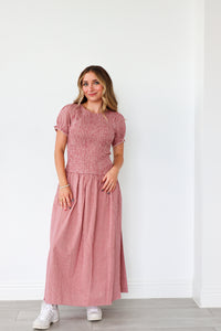 Woman wearing a pink dress standing against a white wall