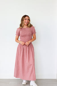 Woman wearing a pink dress standing against a white background