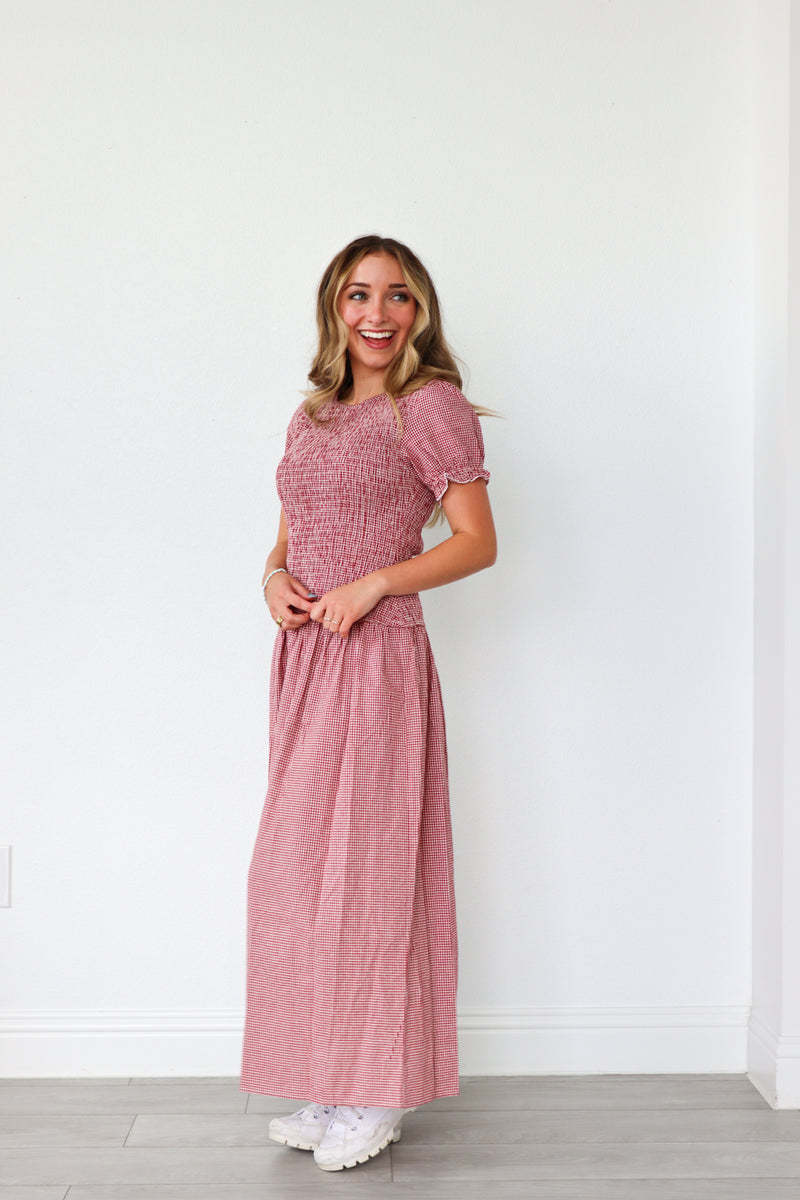 Woman wearing a pink dress standing against a white wall