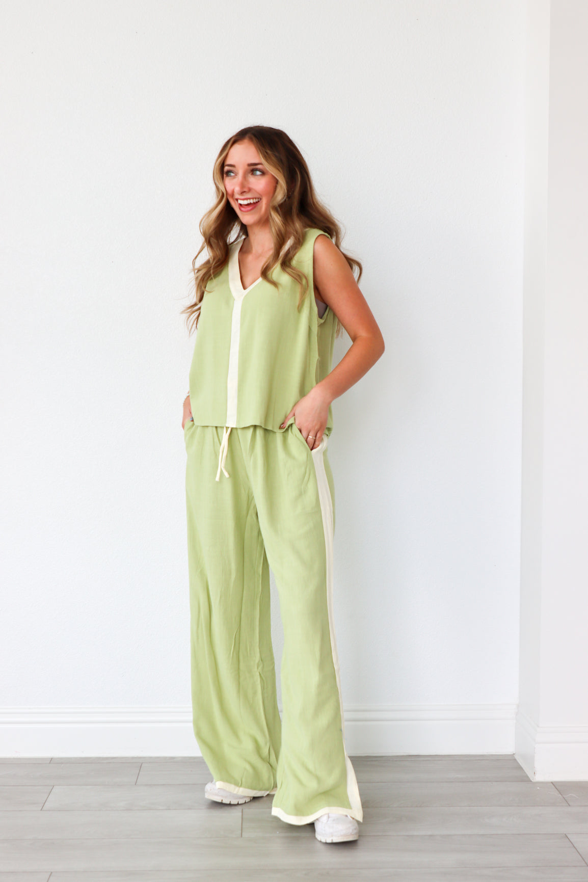 Woman wearing a light green sleeveless top and pants set against a white background