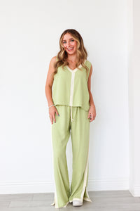 Woman wearing a light green outfit with a white wall background