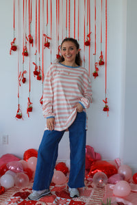Woman standing in a room with red string decorations and balloons on a white wall.