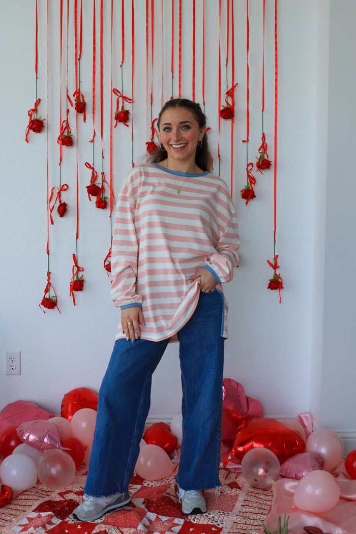 Woman standing in a room with red string decorations and balloons on a white wall.