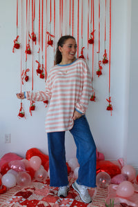 Woman standing in a room with red string decorations and balloons on a white wall.