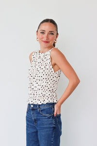 Woman wearing a polka dot top and blue jeans against a plain background