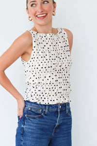Woman wearing a polka dot top and blue jeans against a white background