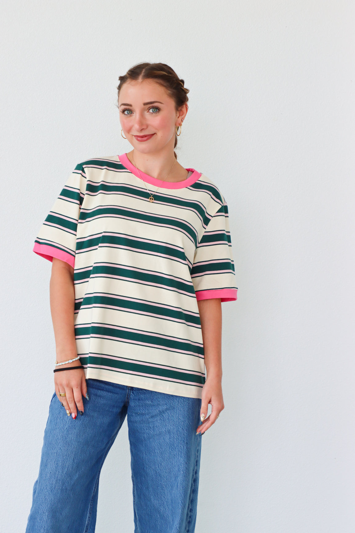 girl wearing white top with dark green stripes and a pink hem