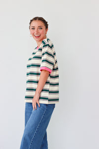 girl wearing white top with dark green stripes and a pink hem