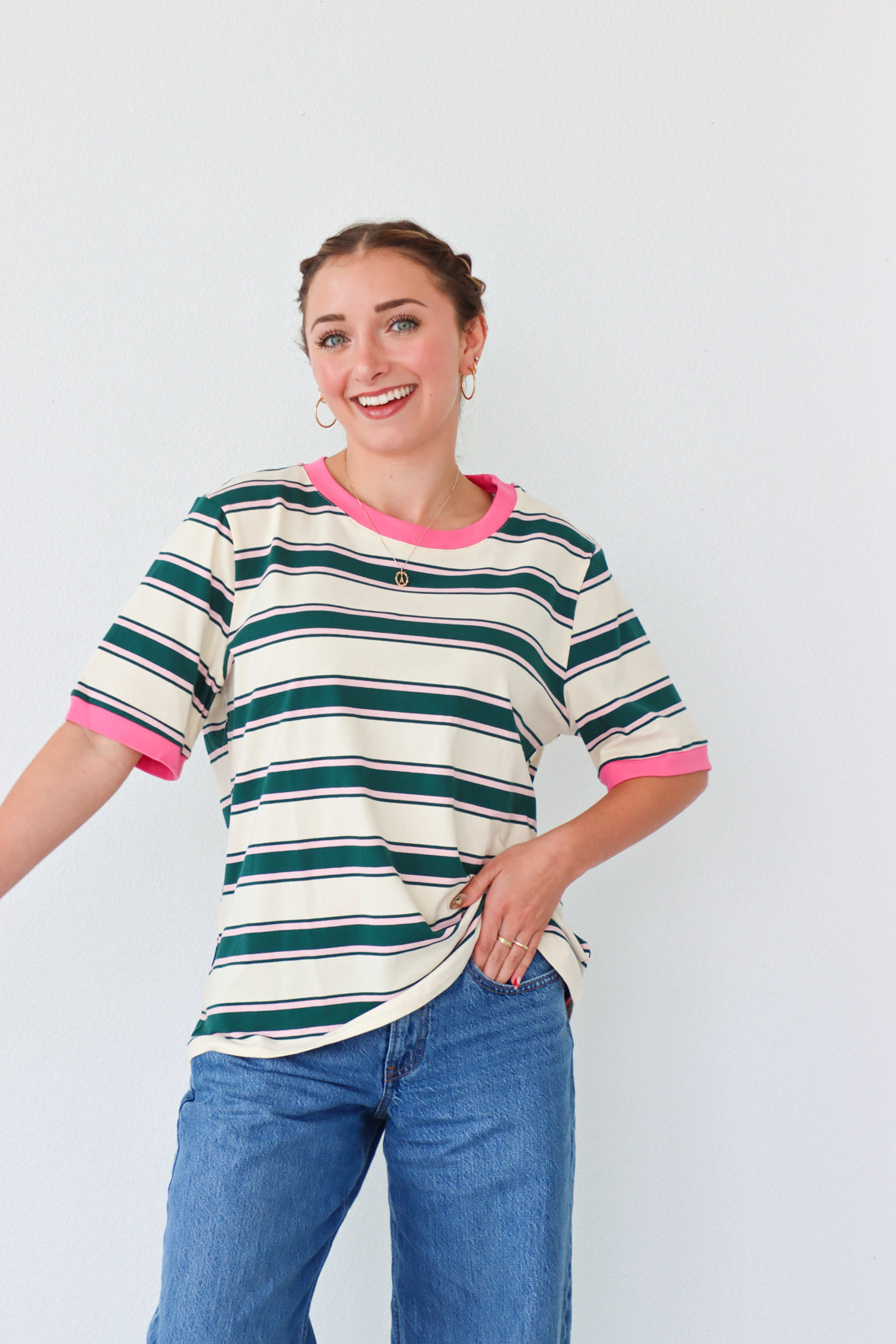 girl wearing white top with dark green stripes and a pink hem