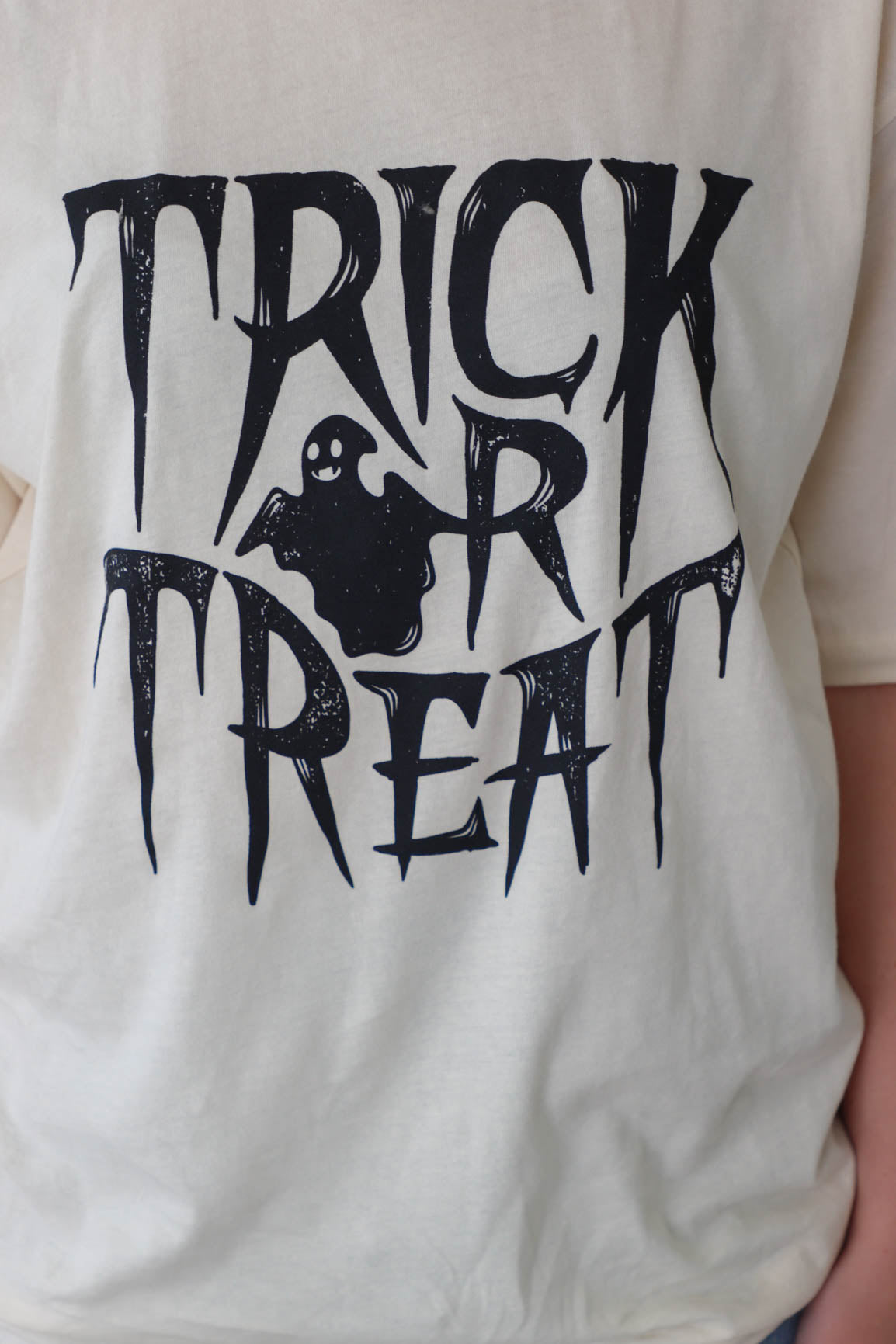 girl wearing cream trick or treat graphic t-shirt