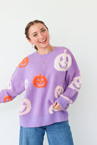 Person wearing a purple sweater with Halloween-themed designs on a white background