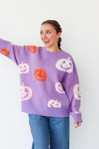 Woman wearing a purple sweater with Halloween-themed pumpkins on a white background