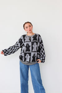 Woman wearing a patterned sweater and jeans against a white background